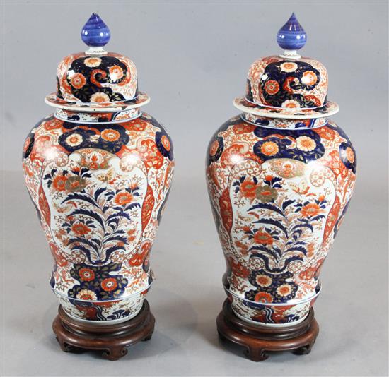 A pair of large Japanese Imari baluster vases and cover, 19th century, height 72.5cm, wood stands, some faults